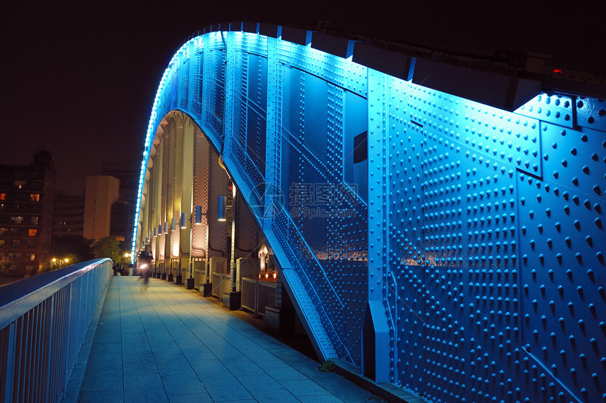 日本东京夜间移动自行车沿永泰桥金属弧形结构的步行道图片