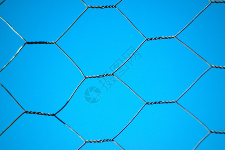 蓝天背景前的铁丝网背景图片