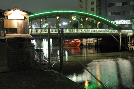 日本东京一条水道内现代照明桥下的传统日本红船图片