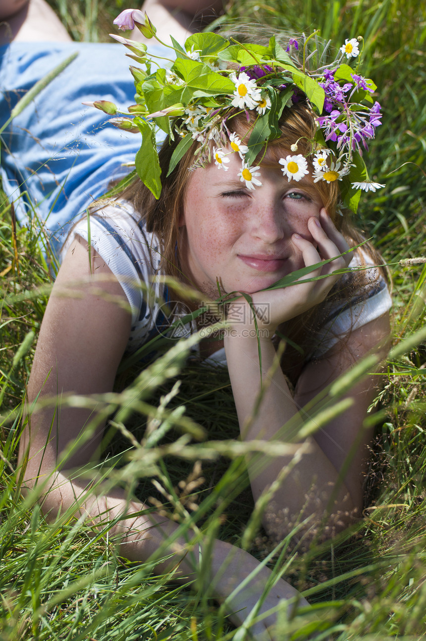 带花圈的红发女孩坐在草地上图片