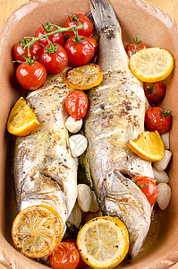 两个烤鲈鱼配番茄和大蒜的砂锅菜图片