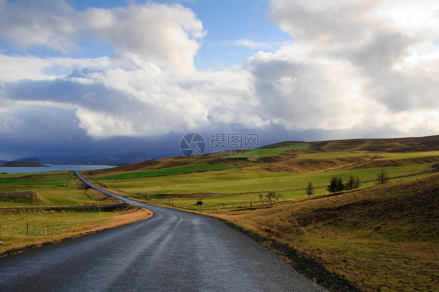 冰岛鲜绿色的田野和丘陵中的道路图片