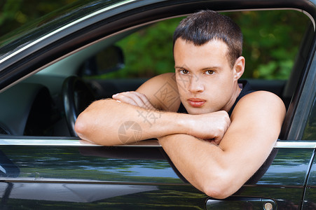 年轻严肃的年轻人像肖一样坐着汽车看似开着窗背景的图片