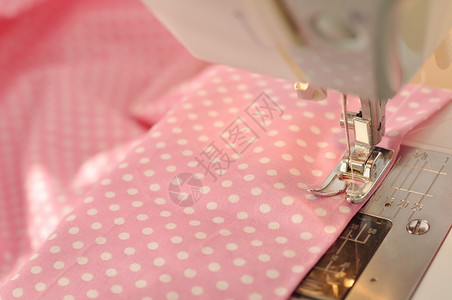 缝纫机细节与粉红色的线和织物图片