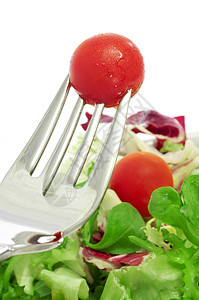 一盘沙拉和叉子里的樱桃番茄的特写图片