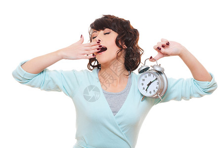 累了的女人拿着闹钟打着哈欠在白图片