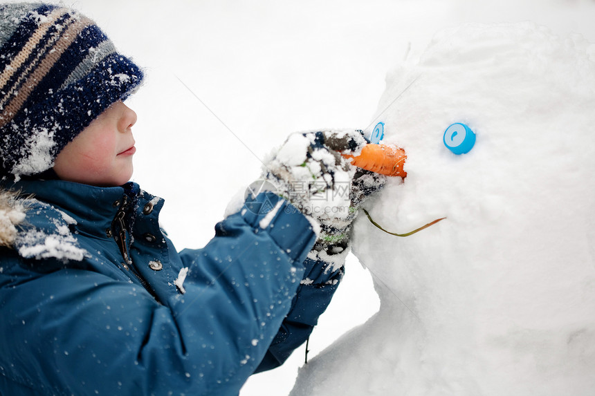 男孩雕刻雪人冬天户外特写图片