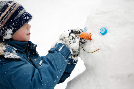 男孩雕刻雪人冬天户外特写图片