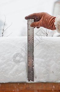 戴手套的手用尺子测量降雪量图片