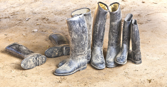 肮脏的塑料马靴站在泥泞的地面上图片