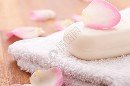 毛巾和木制背景上印着玫瑰叶的肥皂图片