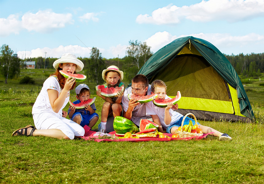 欢乐家庭在公园绿草地野餐享受西瓜的图片