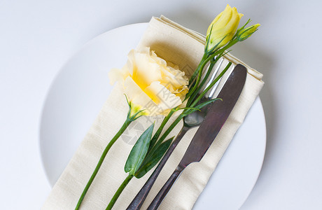 白色背景上的盘子餐具和黄花图片