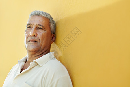 50岁的拉丁裔美国人有问题并仰着黄色墙壁的肖像水平形图片