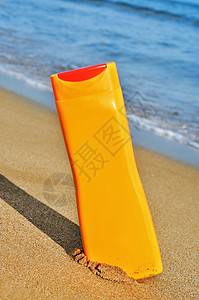 一瓶防晒霜在海滩上的特写图片