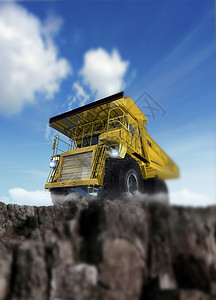 一辆清洁的新的强力黄色地球搬运车在岩石上筑起的建筑卡图片