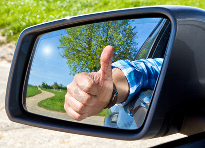 快乐的司机在侧视镜中用拇图片