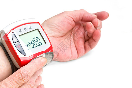 一位用腕式仪表测量血压的老妇人的手高清图片