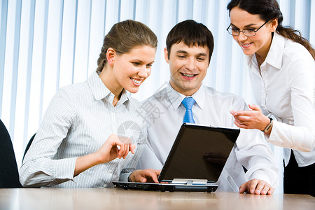 商业会议期间坐在办公室并观看膝上型计算机显示器的商业团队照片单背景图片