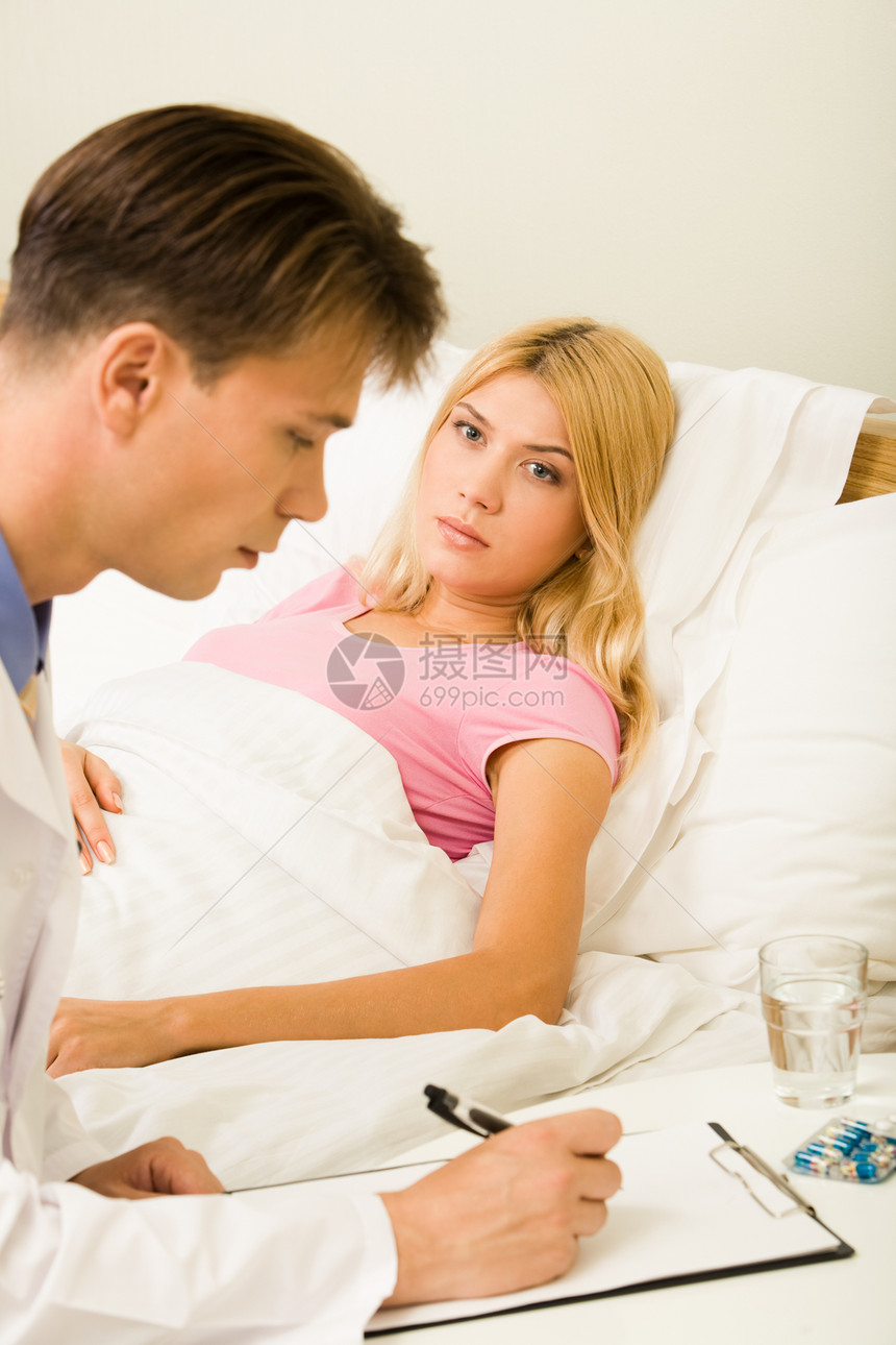 医生为床上的年轻患病妇女提供药物治疗的垂直形图片