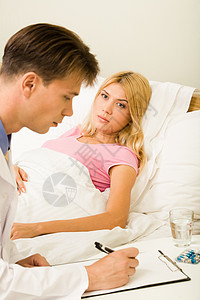 医生为床上的年轻患病妇女提供药物治疗的垂直形图片