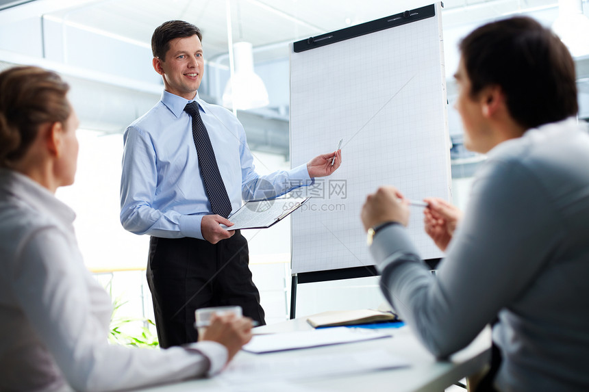 自信的商人和他的伙伴们在白板上讨论一些事情图片