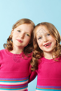 蓝色背景下穿着深红色衣服的快乐双胞胎肖像图片