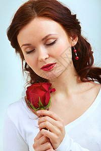 穿着红玫瑰并闻到它香味的迷图片