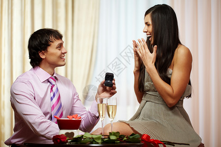 一个年轻男人在求婚时给女友订婚戒指给他的图片