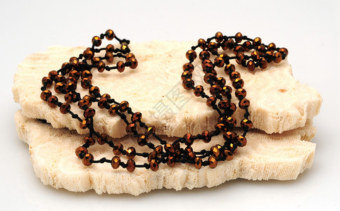 一条漂亮的长的棕色串珠项链挂在珊瑚上图片