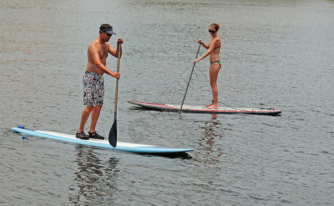 年轻男女情侣在海洋中划桨图片