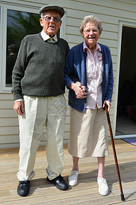 微笑的祖父母在他们家外牵手图片