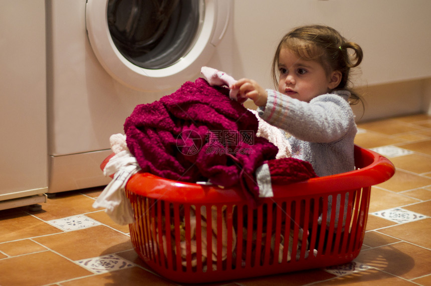 一个可爱小女孩的肖像在红洗衣篮图片