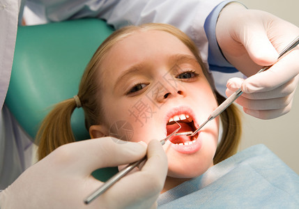 小女孩在接受牙医检查时用张开嘴看照相机的照片图片