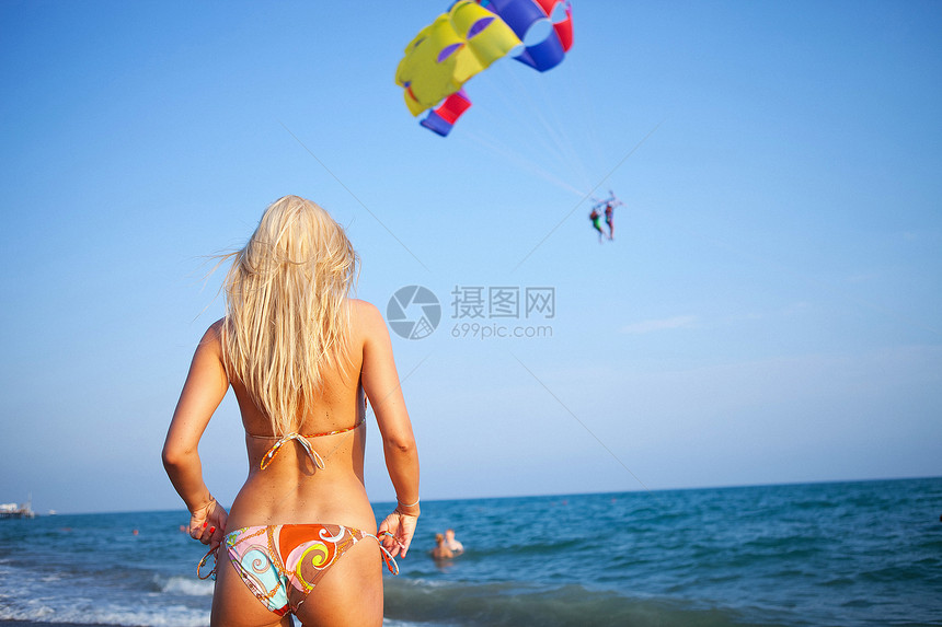 站在沙滩上的感女人期待在她度假时有个滑翔图片