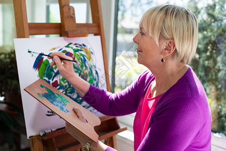 快乐的退休妇女在画布上画在家玩乐图片