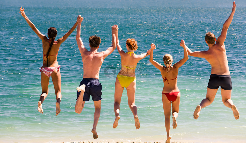 照片中青少年在海边跳跃双手图片