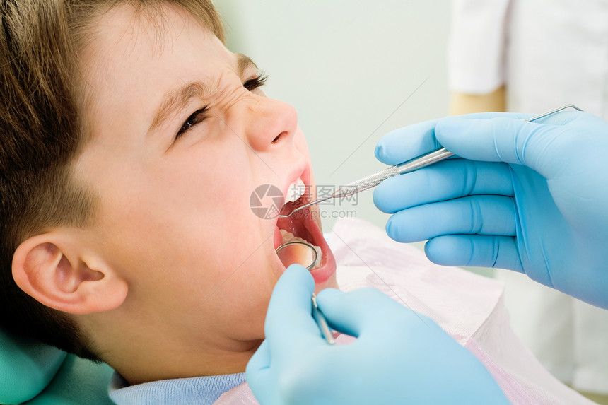 关闭小男孩的嘴在口腔科办公室进行牙图片