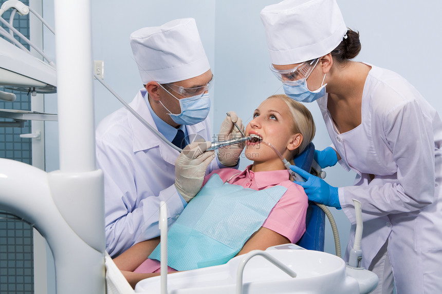 在牙科医生和助理包围下愈合牙齿期间的图片