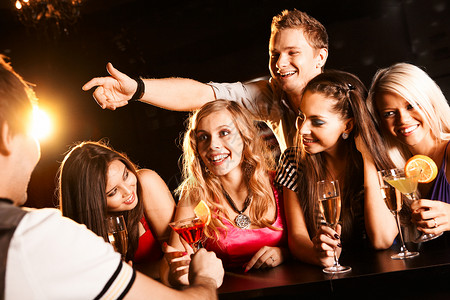 酒吧里快乐的朋友与酒吧男招待交流的照片图片