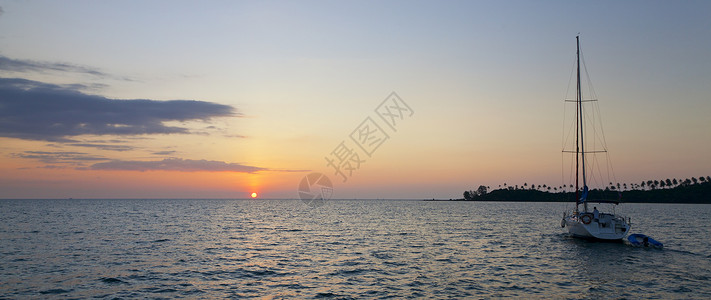 一艘游艇在日落时分航行的全景图像图片