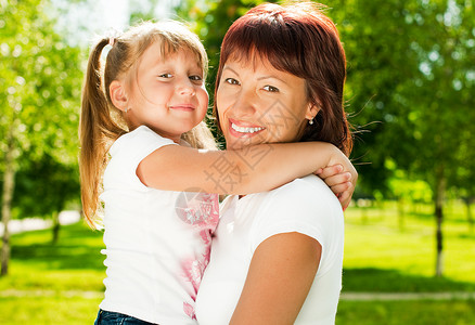 快乐的年轻母亲与美丽的小女儿一起在公园中欢笑图片