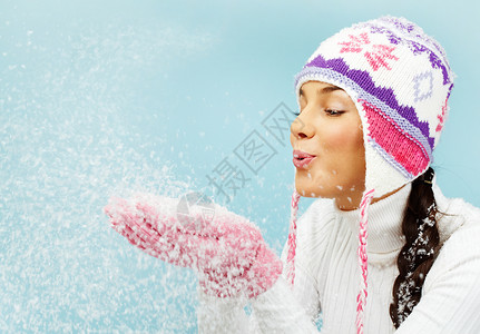 粉红色手套和针织的冬帽从棕榈下吹图片