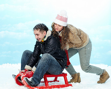 寒假期间幸福的夫妇平底雪橇的肖像图片