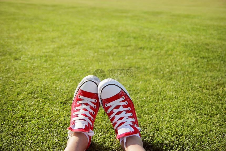 脚穿运动鞋在绿草丛中图片