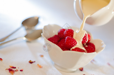 白碗里的草莓里有新鲜的奶油从桌子最亮的柜子上图片