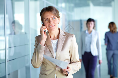 成熟的女商人在办公楼走廊里打电话图片
