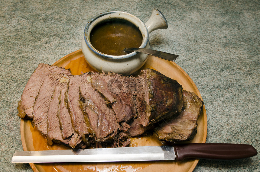 用烤牛肉切片刀和肉汁碗在切肉木板上图片