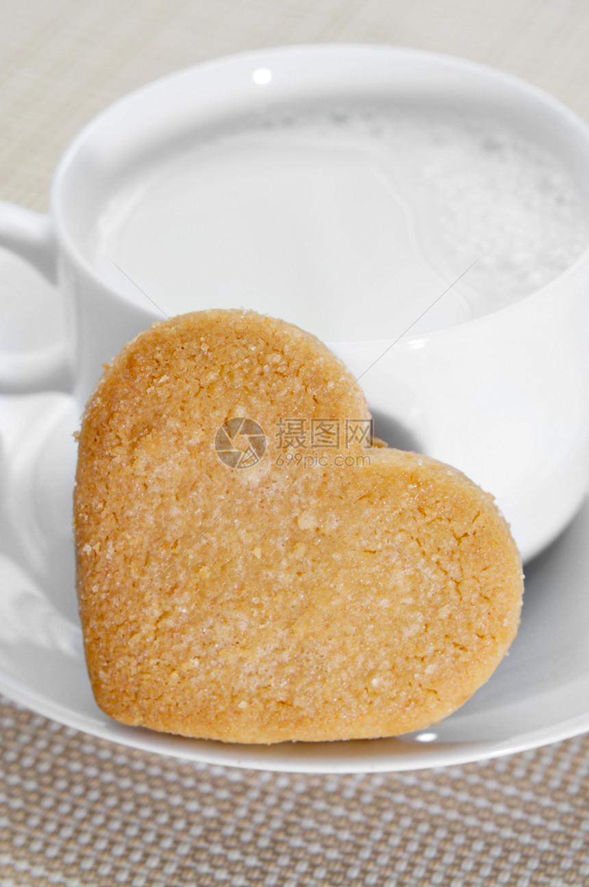 一个心形的脆饼干和一杯牛奶图片