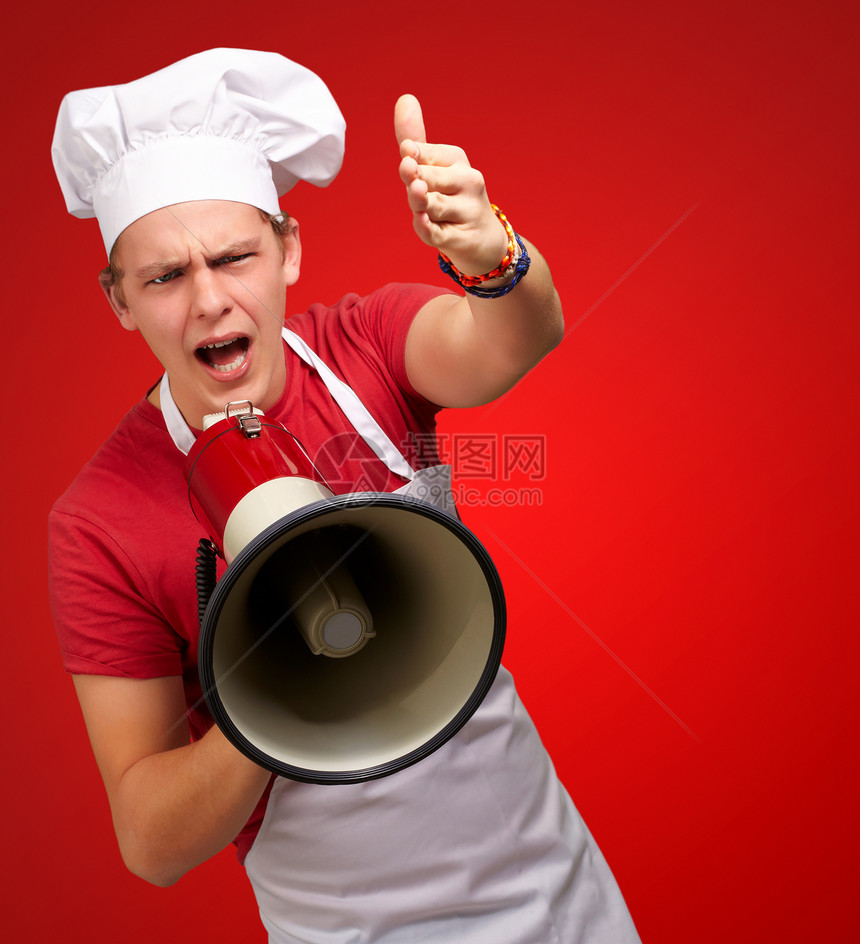 年轻厨师用扩音器喊叫在红色背景图片